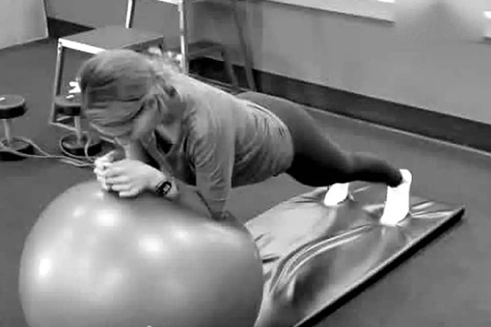 Client holding a plank on a stability ball during a corrective exercise session