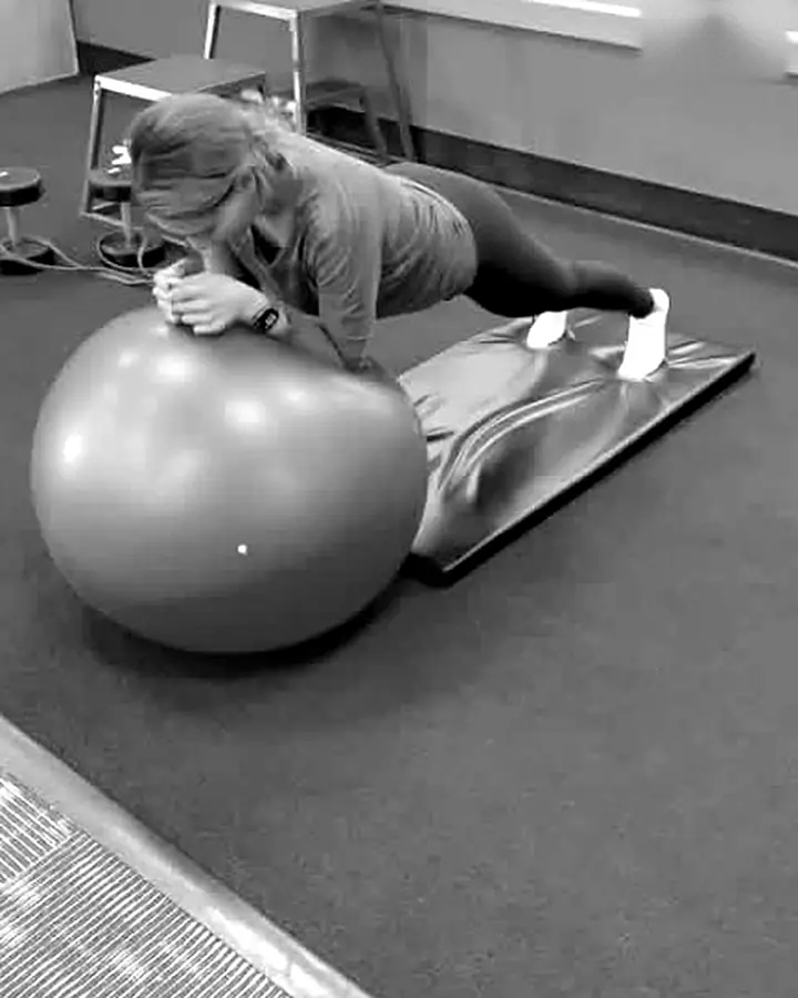 Client holding a plank on a stability ball while Shayan coaches her movement