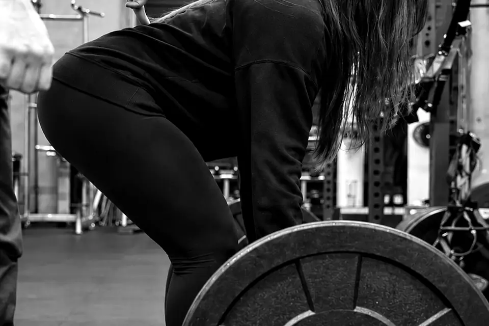 Client deadlifting a loaded barbell while Shayan cues her technique