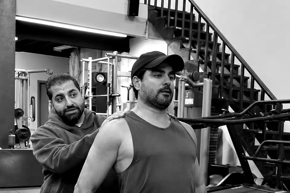 Shayan, in a grey hoodie, coaching a client in the gym
