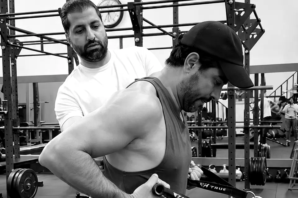 Shayan correcting a client's form on a cable exercise