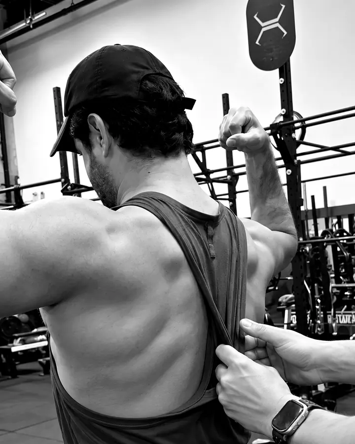 Shayan checking a client's back and lat engagement during a muscle-building session